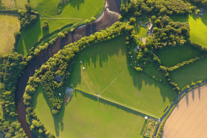 Aerial view of a winding river surrounded by fields and trees in a rural landscape.