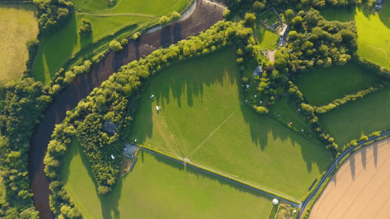 Aerial view of a lush green landscape with winding river and fields.