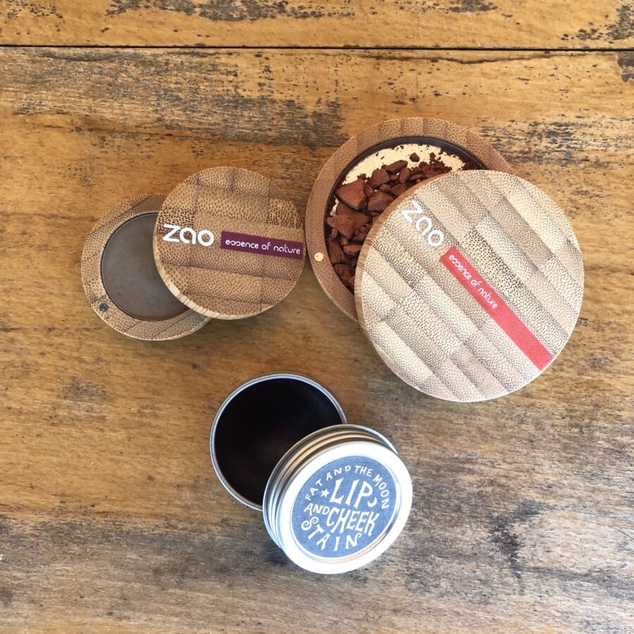 Wooden table with two Zao compacts and a lip and cheek stain tin.