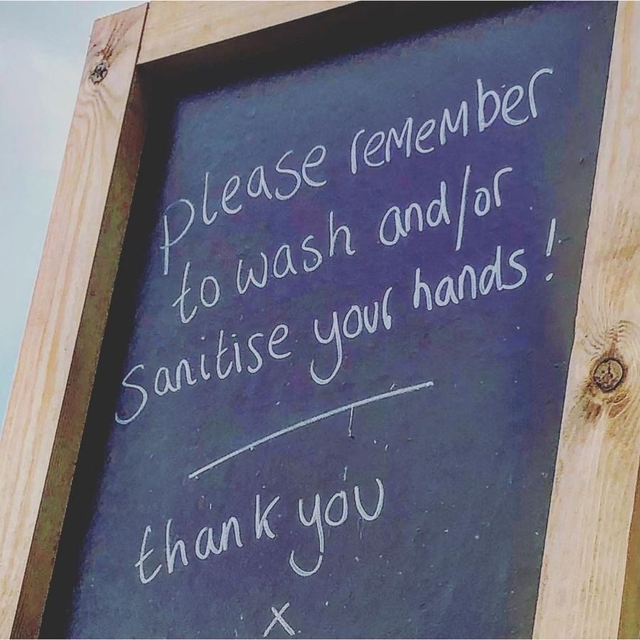 Chalkboard sign reminding people to wash or sanitize their hands, with a wooden frame.