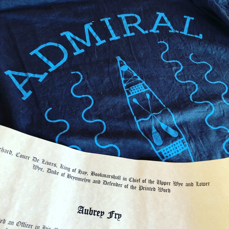 Close-up of blue fabric with 'ADMIRAL' text and a document with 'Aubrey Fry' printed.