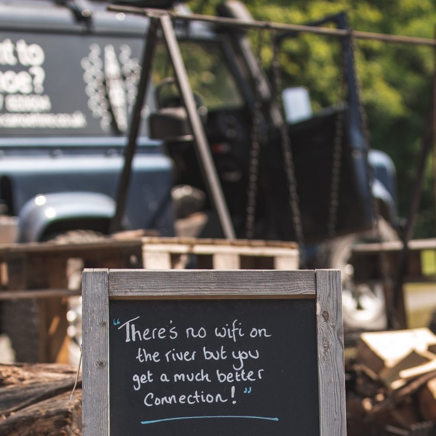 Sign reads 'There's no wifi on the river but you get a much better connection!' with a vehicle in the background.