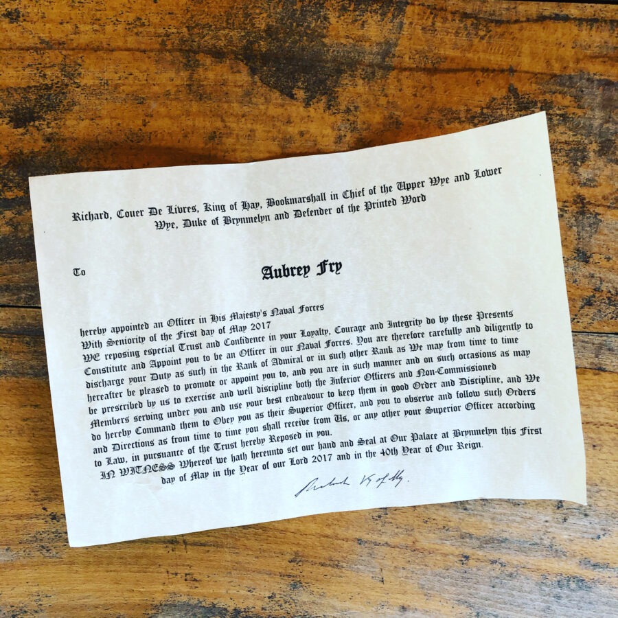 Decorative certificate on wooden surface with black text and ornate fonts.