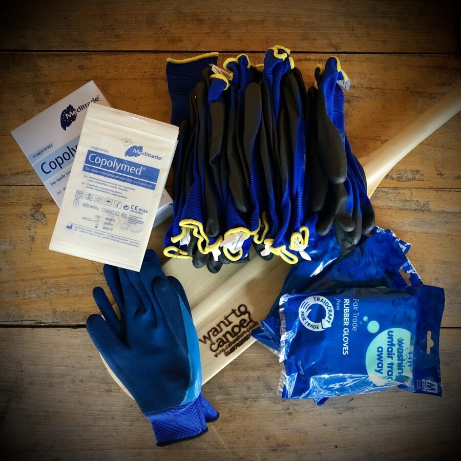 Stack of blue work gloves, Meditrade Copolymed box, and rubber gloves on wooden surface.