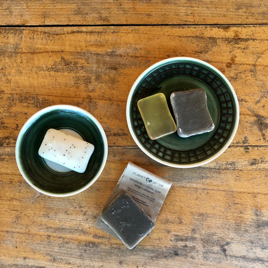 Three bars of soap in green bowls on a wooden table.
